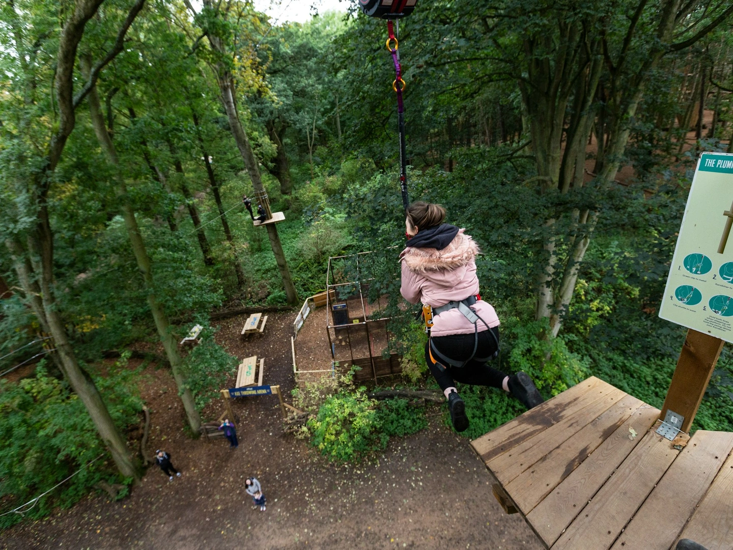 Person steps from a high platform wearing a harness.