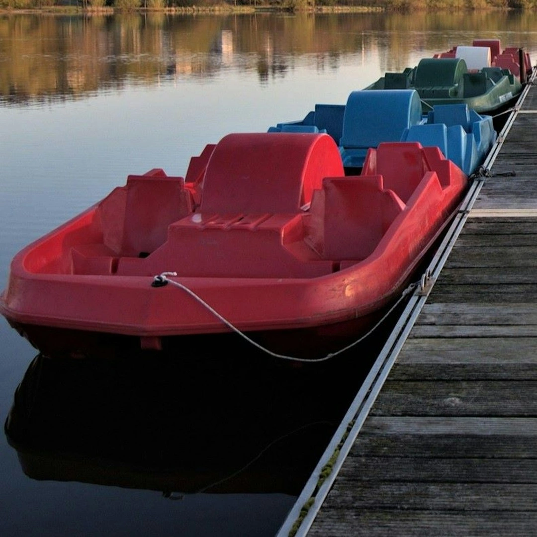 Pedal boats lined up by a jetty on a lake